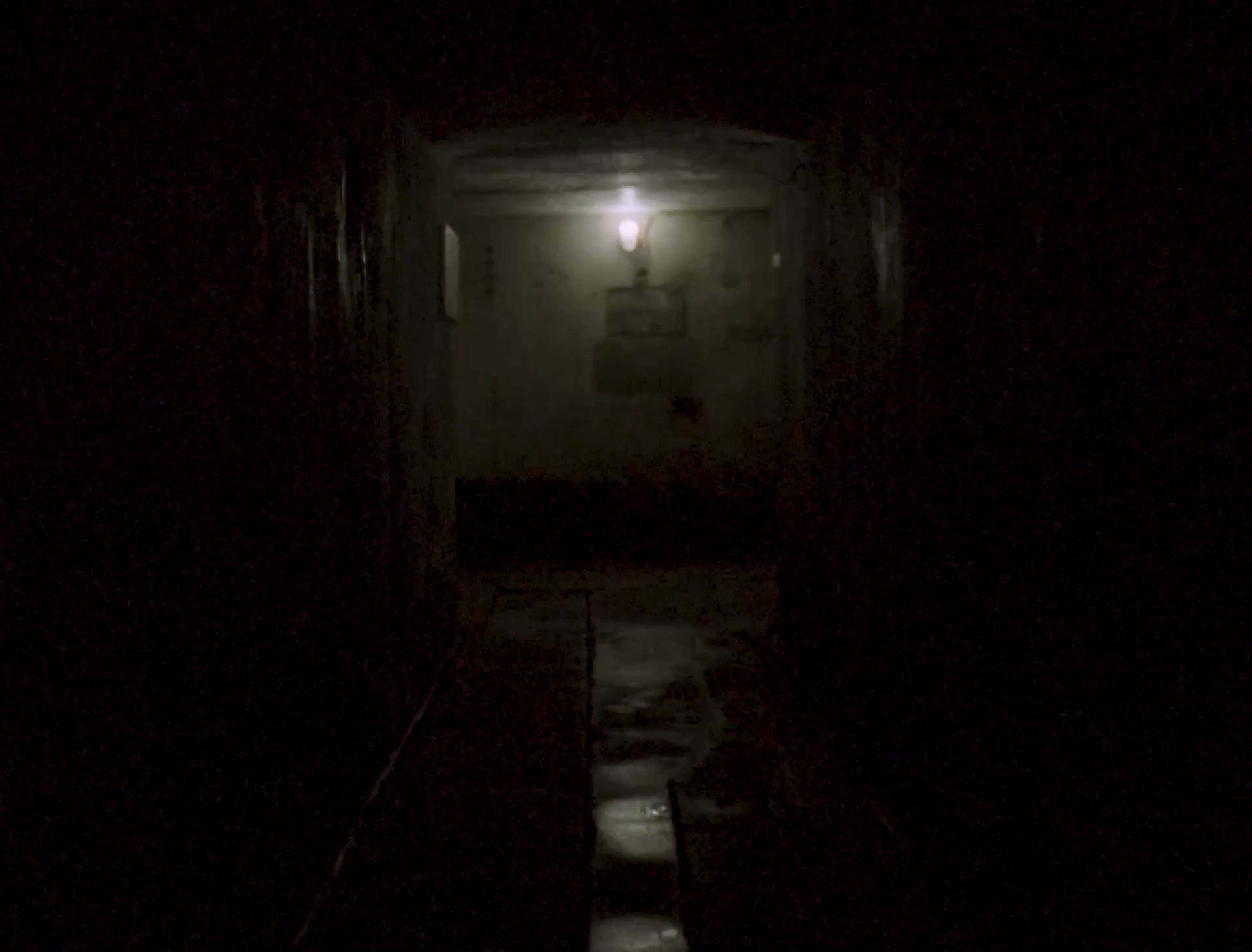Een gang in een bunker, verlicht door één lamp